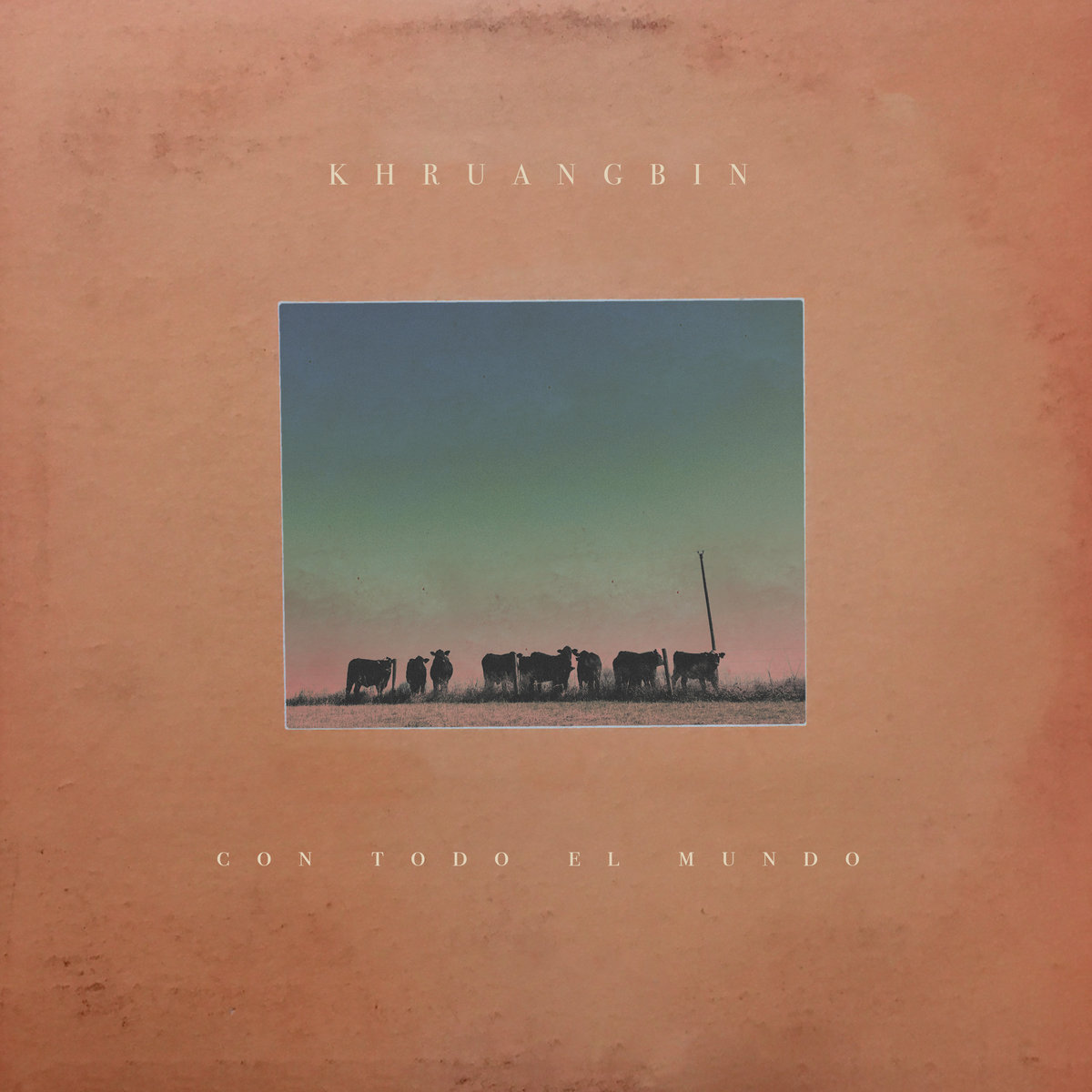 Album cover, "Con Todo El Mundo" by Khruangbin. Features a beige cover with a small photo of cows standing in a field with the title of the album underneath.